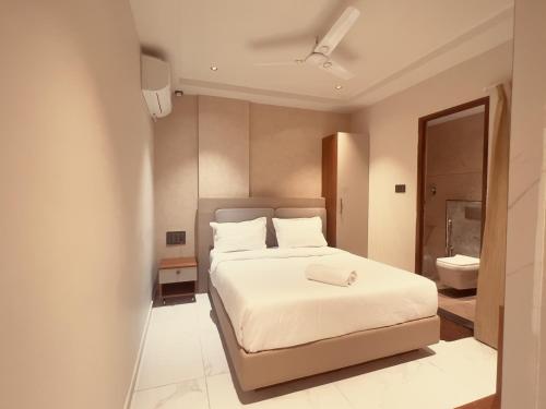 a bedroom with a white bed and a bathroom at Hotel Liora Suites in Bangalore
