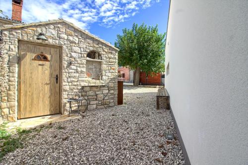 a stone building with a wooden door in a yard at Charming villa Darte with private pool near Rovinj, extra pool heating available in Kanfanar