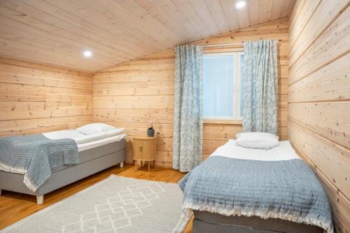 a bedroom with two beds in a wooden cabin at Villa Siltasaari in Sotkamo