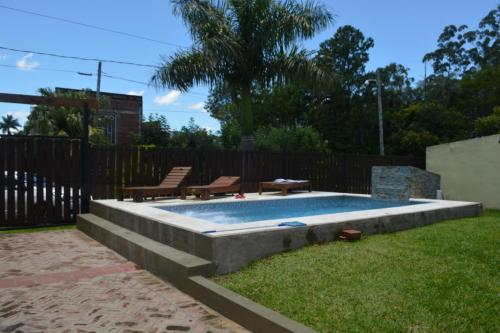 a swimming pool with two chairs and a table at Casa Tapyí Paso in Paso de la Patria
