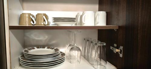a cupboard with plates and dishes on a shelf at Serenity Cottages in Richmond