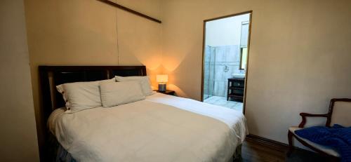 a bedroom with a white bed and a chair at Serenity Cottages in Richmond