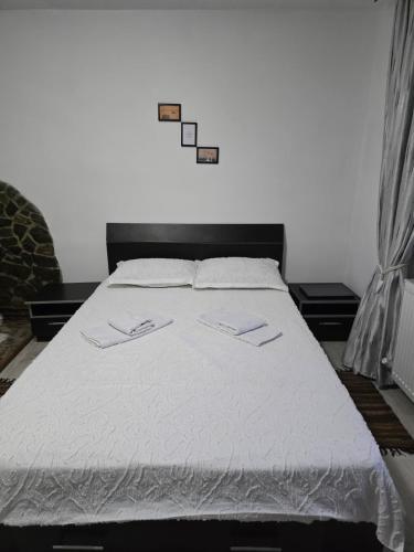 a bedroom with a large bed with white sheets at Cazare la fermă in Galeşu