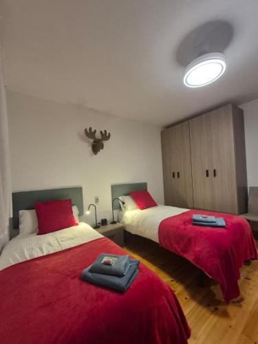 a bedroom with two beds with red blankets at Les 3 Valls in Llavorsí