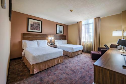 a hotel room with two beds and a desk at Hampton Inn Tampico Zona Dorada in Tampico