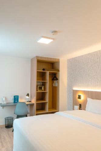 a bedroom with a large white bed and a chair at Fenix Hotel in Quito