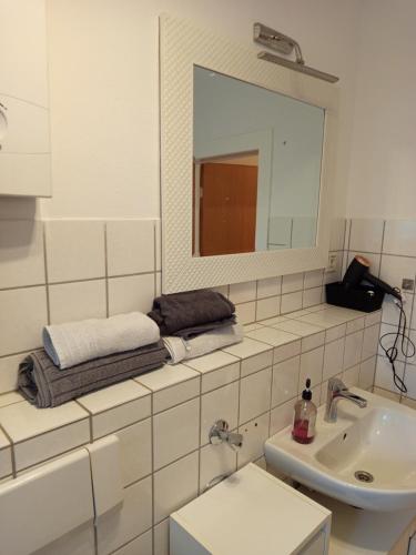 a white bathroom with a sink and a mirror at Bebel apartments in Leverkusen
