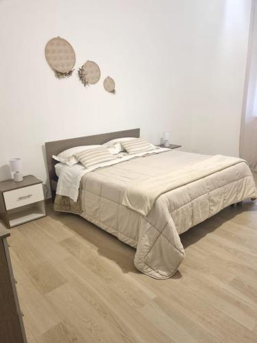 a white bedroom with a bed and a wooden floor at Dimora Mamma Lena in Carovigno
