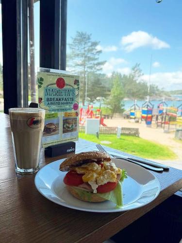 a sandwich on a plate on a table with a drink at Hotel Airisto Marina in Pargas