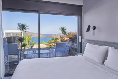 a bedroom with a bed and a view of the ocean at Elounda Olivia Luxury Villa Spinalonga View in Elounda