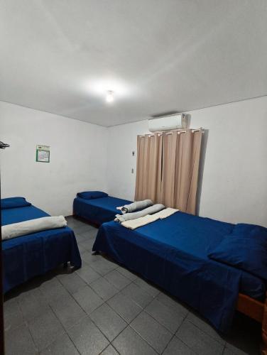 a room with two beds with blue sheets and a curtain at Apto João-de-Barro in Rondonópolis