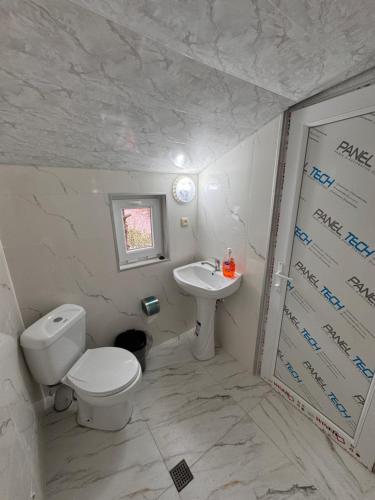 a white bathroom with a toilet and a sink at In the Forest in K'vemo Jocho