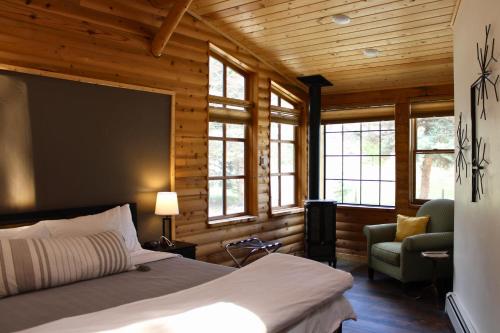 a bedroom with a bed and a chair and windows at Two Bridges Lodge in Bailey