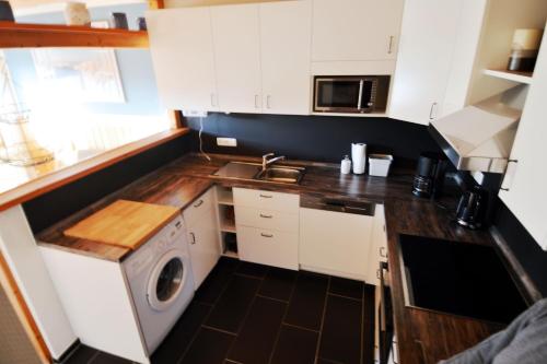 a small kitchen with white cabinets and a washer at Windstill - Wendstrasse 16 in Heiligenhafen