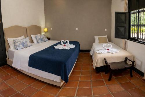 a bedroom with two beds with white flowers on them at Hotel Hacienda Supracafe in Popayan