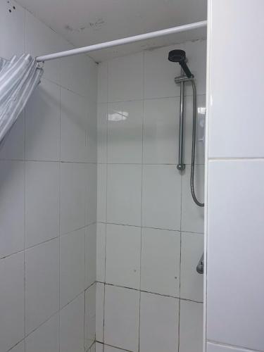 a shower in a bathroom with white tiles at Compact single room A near Heathrow with 24 hour buses to all terminals in Feltham