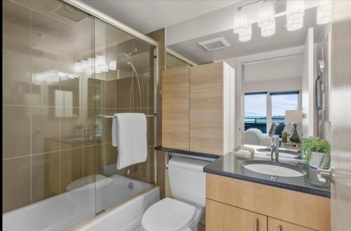 a bathroom with a toilet and a sink and a bath tub at Luxury, ocean view Condo with deck and indoor pool in Seattle