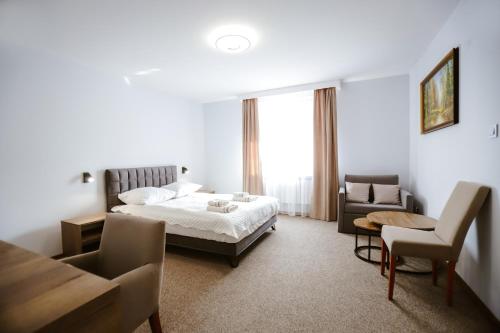 a bedroom with a bed and a couch and a table at Hotel Lubaczów Hotel Restauracja u Dina in Lubaczów