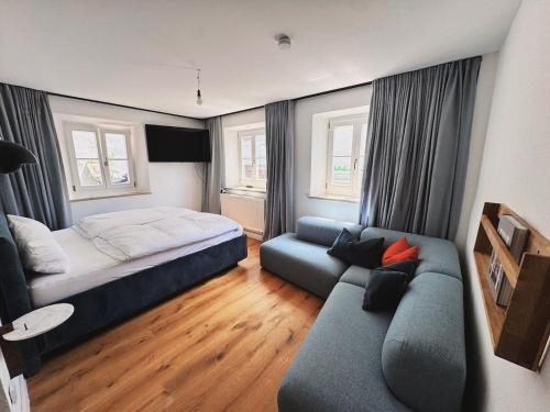 ein Schlafzimmer mit einem Bett und einer Couch in der Unterkunft TheBlueInn in Wasserburg am Inn
