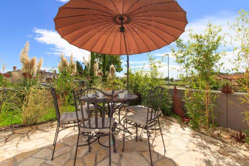 a table and chairs under an umbrella on a patio at Charming villa Darte with private pool near Rovinj, extra pool heating available in Kanfanar