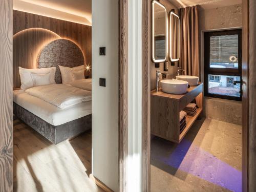 a bedroom with a bed and a sink and a mirror at Corones Suites - Dolomites Residence in Valdaora
