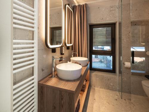 a bathroom with two sinks and a large mirror at Corones Suites - Dolomites Residence in Valdaora