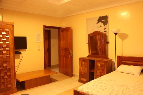 ein Schlafzimmer mit einem Bett und einem Fernseher in der Unterkunft Londoninnn Brusubi Heights 4U in Brusubi