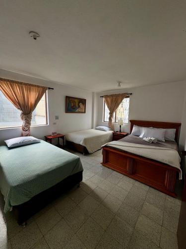 ein Schlafzimmer mit zwei Betten und zwei Fenstern in der Unterkunft Hotel Tahami in Sonsón