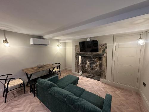 a living room with a green couch and a fireplace at Akroyd House - The Piece Hall Room in Halifax