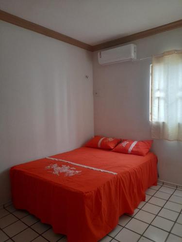 a room with a bed with an orange sheet on it at Solares Residence in Teresina