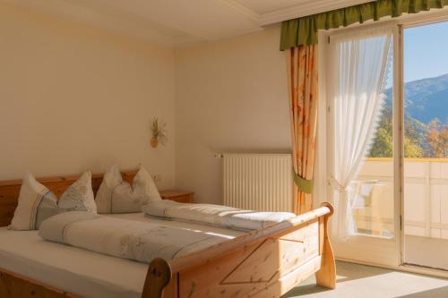 ein Schlafzimmer mit einem Bett und einem großen Fenster in der Unterkunft Hotel Roduna in Rodeneck