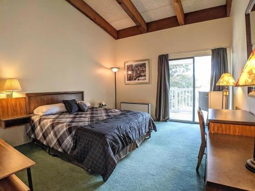 a bedroom with a bed and a desk and a window at Spacious 2 bd 2 bth Condo at Cedar Lodge Laconia in Laconia