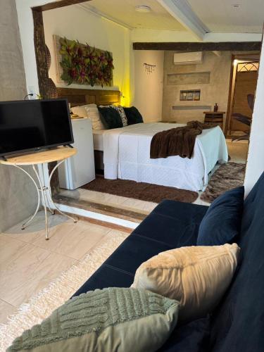 a room with two beds and a tv and a couch at Pousada Sonho Real in Angra dos Reis