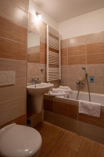 a bathroom with a toilet and a sink and a tub at Vila Araya Mlynica in Mlynica