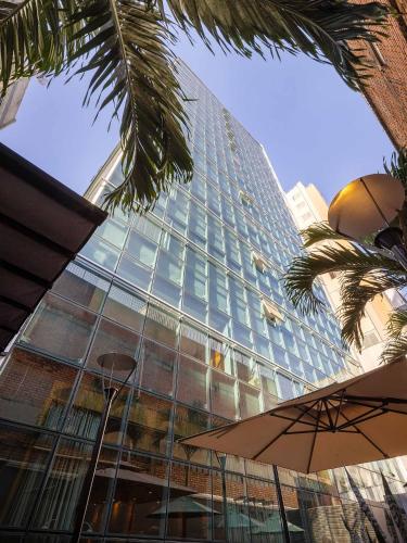 a tall glass building with a palm tree in front of it at Hotel Park Tower Savassi by Nacional Inn in Belo Horizonte