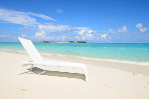 a white chair sitting on a beach near the ocean at One bedroom condo at ONE Cable Beach in Nassau