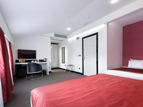 a hotel room with a red bed and a desk at Nova City Garni Hotel Signature Collection in Belgrade