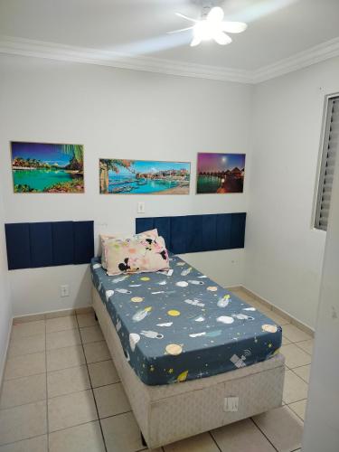a bed in a room with paintings on the wall at apartamento atras do shopping Iguatemi 2 quartos in Votorantim