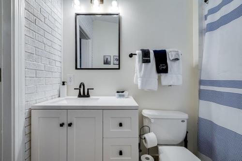 a white bathroom with a sink and a mirror at Charming Historic Condo with Pool in Savannah