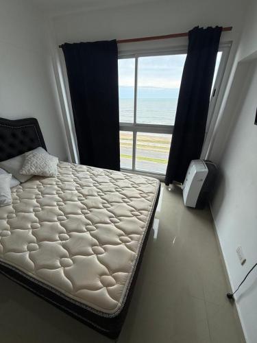 a bed in a room with a large window at Edificio lillion 2 in Mar del Plata