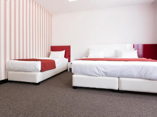 two beds in a hotel room with white and red at Nova City Garni Hotel Signature Collection in Belgrade