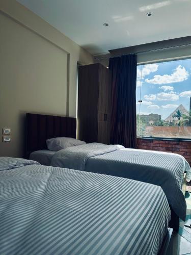 two beds in a hotel room with a window at Atlantis pirámides view Inn in Cairo