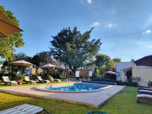 a swimming pool in a yard with chairs and umbrellas at La Casona Minera in Mineral de Pozos