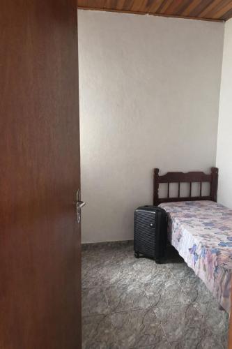 a bedroom with a bed and a suitcase next to a door at Casa Central Aconchegante in Cunha