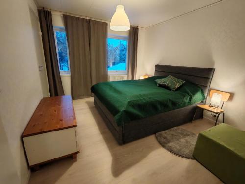 ein Schlafzimmer mit einem grünen Bett und einem Tisch in der Unterkunft Ailotar in Inari