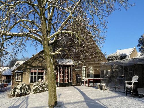 a house with a tree in the snow at Farmhouse in Nieuwleusen near Lake and Nature in Bergen op Zoom