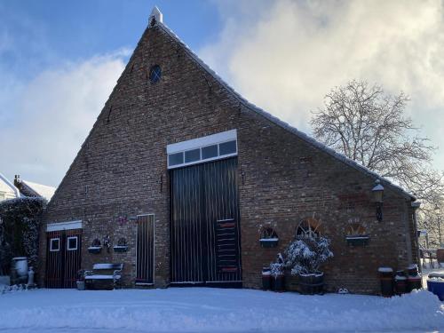 a large brick building with a large door in the snow at Farmhouse in Nieuwleusen near Lake and Nature in Bergen op Zoom