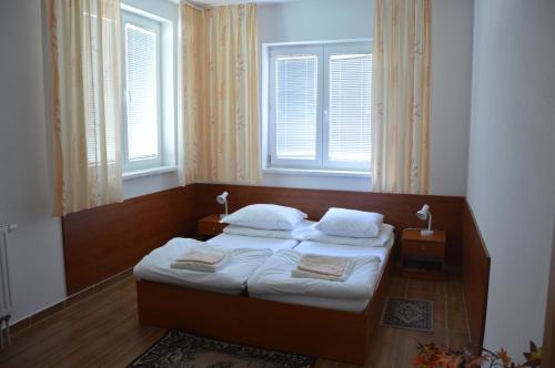 a bedroom with a bed with two pillows and two windows at Penzion PKO Nitra in Nitra