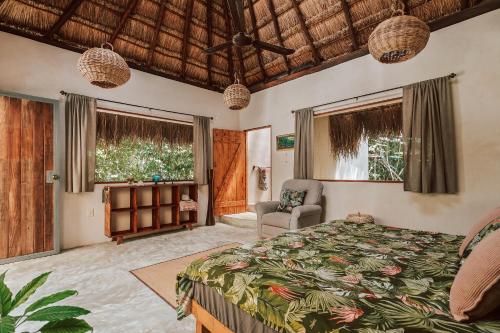 a bedroom with a bed and a chair and windows at Casa Arkaana Eco Retreat in Tulum