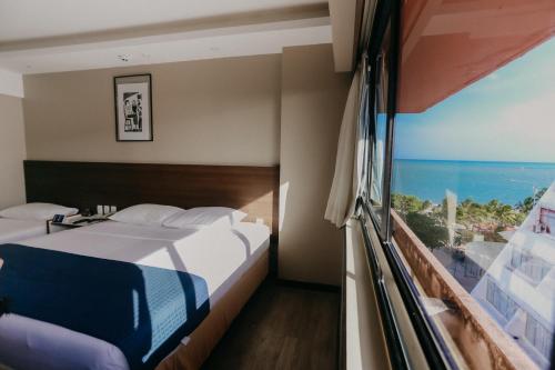 a bedroom with a bed and a view of the ocean at Pajuçara Praia Hotel in Maceió
